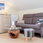 Wohnzimmer mit Sofa, Couchtisch und Schrank unter Dachschrägen.