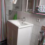 Badezimmer mit Waschbecken, Spiegel und Dusche. Handtuch und Fliesen sind sichtbar.