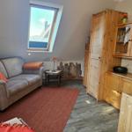 Wohnraum mit Sofa, Holzmöbeln und Dachfenster. Teppich und Kissen in Rot.