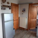 Küche mit Kühlschrank, Holztüren und Heizkörper an der Wand.