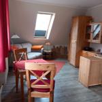 Wohn- und Essbereich mit Holzmöbeln, Sofa, Tisch und Stühlen. Dachfenster und Holzwand.