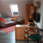 Wohnraum mit Sofa, Schreibtisch und TV. Dachfenster und Holzmöbel.