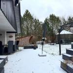 Schneebedeckter Garten mit Terrasse, Sonnenschirm und Whirlpool.