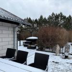 Schneebedeckter Garten mit Sitzgelegenheiten und Statuen. Im Hintergrund sind Bäume und ein Pavillon sichtbar.
