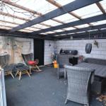 Terrasse mit Sitzgruppe, Grill und Pergola unter transparentem Dach.