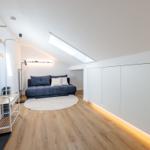 Zimmer mit Sofa, Kleiderständer und Schrank unter Dachschrägen