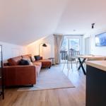 Wohnbereich mit Sofa, Esstisch und TV. Balkon mit Bergblick.