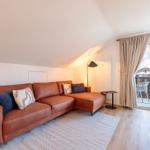 Wohnzimmer mit braunem Sofa, Glasfront und Balkon.