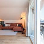 Wohnzimmer mit braunem Sofa, Balkon und Blick auf Berge.