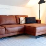 Ein braunes Ledersofa mit Kissen auf einem Teppich.