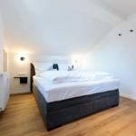 Schlafzimmer mit Doppelbett, Holzboden und schrägen Wänden.