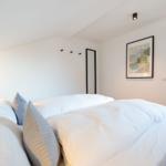 Schlafzimmer mit Bett, Wandbild und Tür zum Wohnbereich.