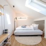 Schlafzimmer mit Dachschrägen, Dachfenster, Bett und Kleiderständer.