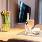 Tisch mit Tulpen, Sektflasche und Gläsern vor TV und Fenster