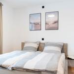 Schlafzimmer mit Bett, Fenster und Wandbildern.