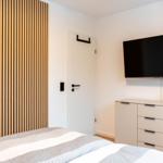 Schlafzimmer mit Bett, TV und Holzwand