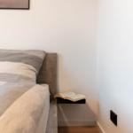 Schlafzimmer mit Bett, Kissen und offenem Buch auf Nachttisch.