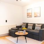 Ein Wohnzimmer mit grauem Sofa, Holztisch und Wandbildern.