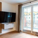 Wohnzimmer mit TV, Balkon und Holzboden