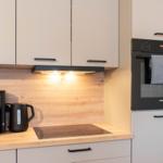 Küche mit Dunstabzug, Kaffeebereiter und integriertem Ofen.