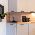 Küche mit Holzrückwand, Spüle, Kaffeemaschine und Küchengeräten.