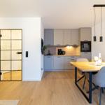 Moderne Küche mit Essbereich und Glaswand. Holzboden und schlichte Möbel.