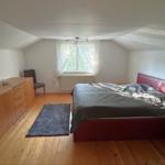 Schlafzimmer mit Dachschrägen, Bett, Schrank und Fenster.