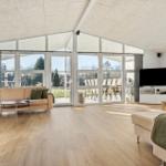 Living room with large windows, sofa, TV, and wooden floor.
