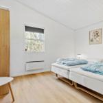 Two beds with blue blankets, window, wooden floor, and wall pictures.
