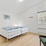 Room with double bed, green armchair, and window with tree view.