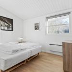 Bedroom with double bed, wooden floor, and window with view of trees.