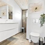 Bathroom with sink, toilet, and shower. White built-in vanity and wooden ceiling.