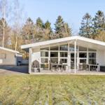 Modern white villa with large terrace and garden. Forest in the background.