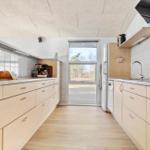 Modern kitchen with light cabinets, granite countertops, and window to outdoor area.