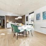 Dining room with green chairs and tablecloth. Kitchen area and window visible.
