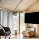 Living room with wooden walls, TV, two armchairs, and view of nature.