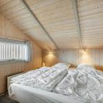 Bedroom with wooden walls and double bed. Window and wall lights visible.