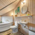 Bathroom with bathtub, toilet, and sink against wooden wall