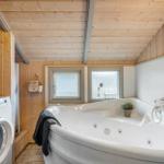 Bath with whirlpool, washing machine, and wood wall.