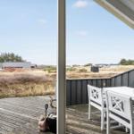 Terrace with white table and chairs, view of grassland and houses.