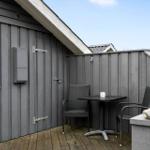Terrace with table and two chairs, wooden floor and gray wood wall.