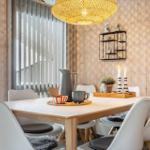Dining room with wooden wall, dining table and white chairs. Outside is a balcony visible.