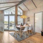 Dining room with table, chairs, and fireplace. Entrance to terrace with sea view.