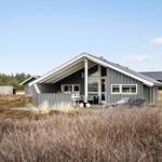 A gray vacation house with a terrace and loungers in a natural setting.