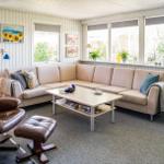 Living room with sofa, leather chair, and windows overlooking the garden.