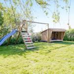 Backyard with climbing frame, slide, swing, and wooden hut.