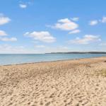 Beach with sand and sea under blue sky with white clouds.