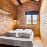 Bedroom with wooden walls, bed, and window