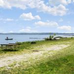 Green lakeside area with picnic tables and boats on the water.
