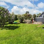 Green garden with flowers, hammock, and wooden house in background.